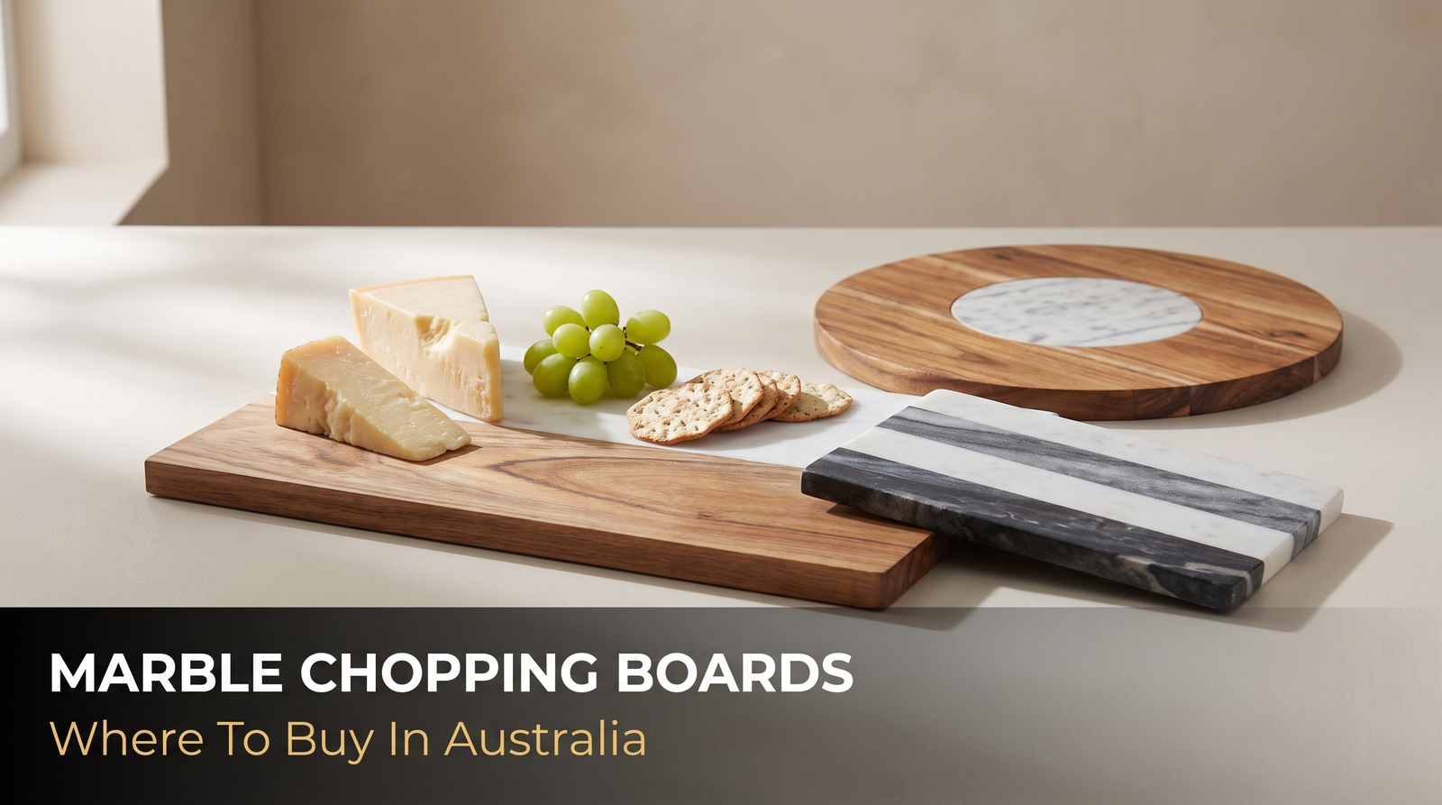 Three marble and acacia serving boards on a kitchen bench with cheese, grapes and crackers