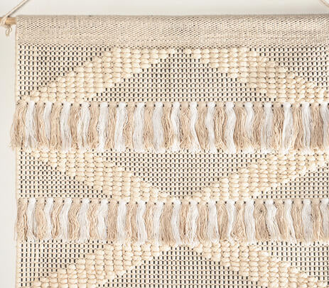 White and beige cotton wall hanging shown grouped in a layered gallery wall