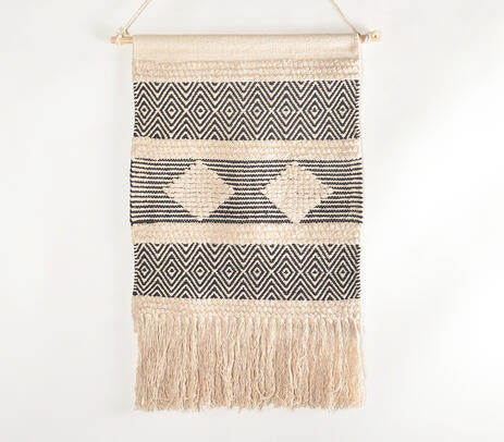 Handwoven geometric cotton wall hanging on a painted plaster wall