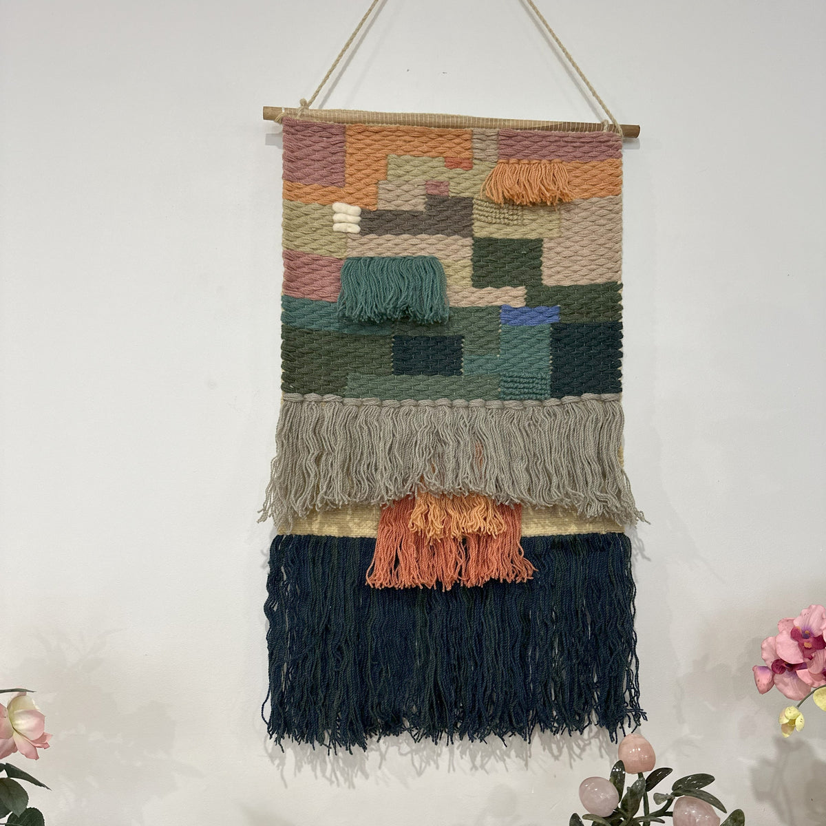 Earthy diamond wool wall hanging on a plain wall
