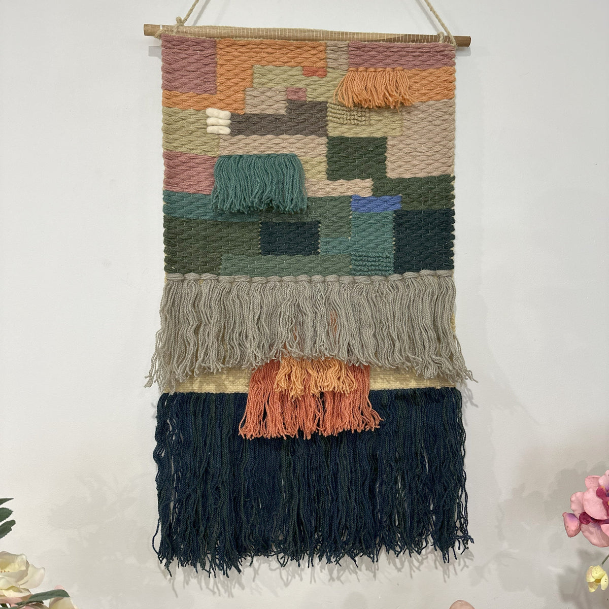 Earthy diamond wool wall hanging styled in a boho corner