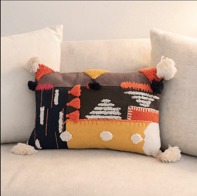 Grey embroidered lumbar cushion cover styled on a bed